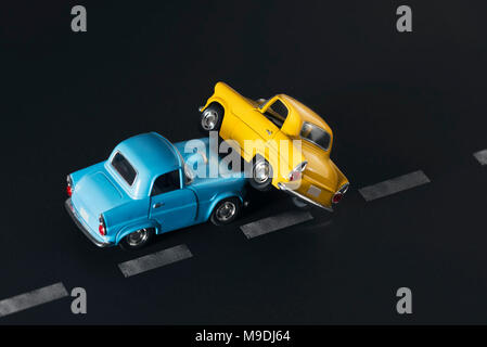 Accident de la circulation par deux petites voitures bleu et jaune sur fond noir avec des voies routières. Banque D'Images