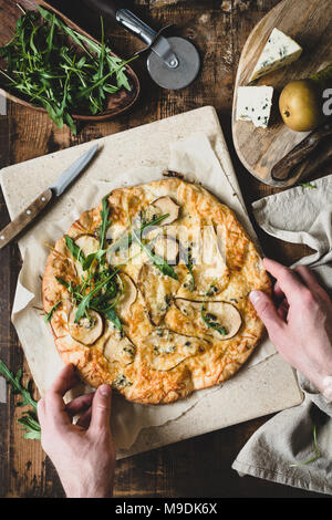 Mains tenant quatre fromages pizza à la poire. Quatro formaggi pizza à la poire. Vue d'en haut Banque D'Images