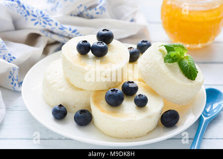 Syrniki, fromage cottage, crêpes ou gâteaux au fromage avec les baies fraîches et de miel. Vue rapprochée. Un petit-déjeuner sain, healthy dessert ou une collation Banque D'Images