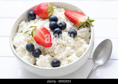 Tvorog, les agriculteurs de fromage, de fromage blanc ou de fromage cottage en blanc bol à fruits d'été frais, vue rapprochée. Riche en calcium des aliments sains Banque D'Images