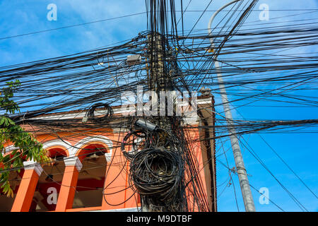 Désordre énorme enchevêtrement de dizaines de câbles électriques en haut d'un poteau d'électricité, Cambodge Banque D'Images