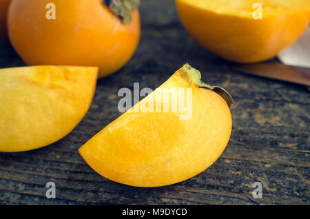 Tranche de delicious fresh ripe fruit kaki kaki sur la vieille table en bois. Banque D'Images