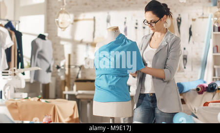 Belle femme la mode, designer, travaillant avec la couture Mannequin, essayant sur Ornements divers et des tissus. Son studio est lumineux et ensoleillé. Banque D'Images