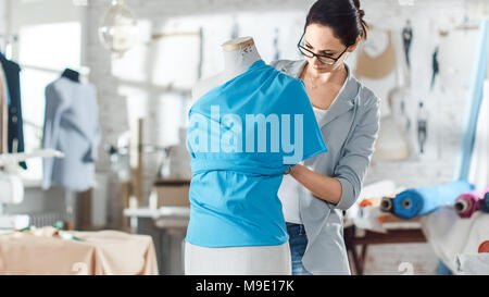 Belle femme la mode, designer, travaillant avec la couture Mannequin, essayant sur Ornements divers et des tissus. Son studio est lumineux et ensoleillé. Banque D'Images