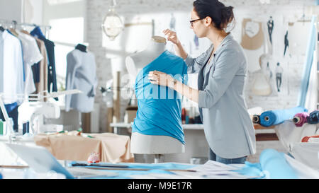 Belle femme la mode, designer, travaillant avec la couture Mannequin, essayant sur Ornements divers et des tissus. Son studio est lumineux et ensoleillé. Banque D'Images