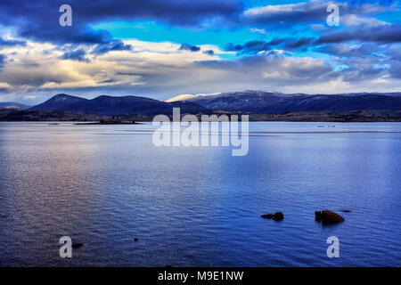 Lake Jindabyne Snowy Mountains dans la région d'hiver de NSW en Australie au lever du soleil. Sommets de montagnes couvertes de neige lointain sous ciel bleu et nuages orageux r Banque D'Images