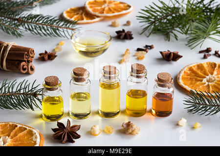 Sélection de Noël d'huiles essentielles et d'épices sur fond blanc : bouteilles d'huile essentielle, d'épinettes, de sapins, de résine d'encens, l'anis étoilé, la cannelle, Banque D'Images
