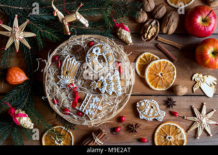 Gingerbread cookies de Noël décoré dans un panier en osier, avec des branches d'épinette, de la paille, ornements, noix, pommes cannelle, l'anis étoilé, rose h Banque D'Images