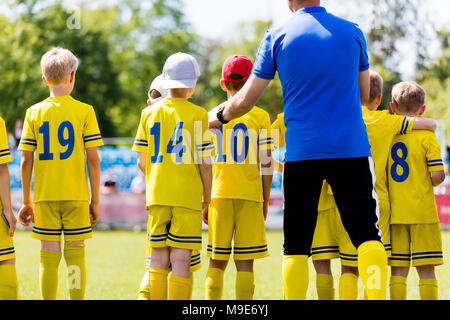 L'entraîneur de football des jeunes de parler à l'équipe de soccer pour enfants. Jeunes joueurs de football avec l'entraîneur. Entraîneur de football l'encadrement à l'audience. Banque D'Images