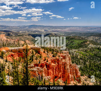 Un panorama de Bryce Canyon avec ses falaises escarpées et la vallée ci-dessous sous un ciel avec des nuages blancs moelleux. Banque D'Images