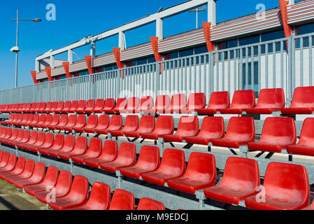 Gradins rouge vide se dresse sur un stade de football avec un ciel bleu Banque D'Images