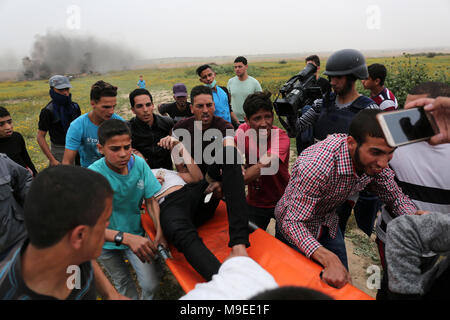 Gaza, Territoires palestiniens. 23 mars, 2018. Les hommes palestiniens aider à évacuer un manifestant blessé lors d'affrontements avec les troupes israéliennes près de Khan Yun Banque D'Images