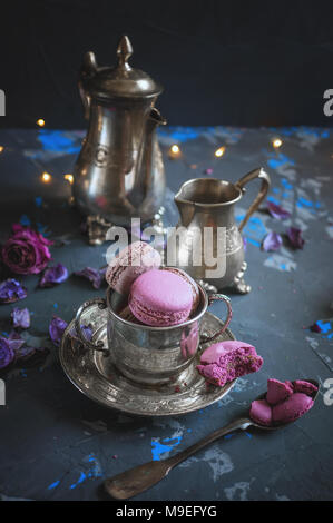 Des petits macarons sur une coupe de métal de l'argent avec de l'effet bokeh voyants sur le fond en bois. Focus sélectif. Spase copie Banque D'Images