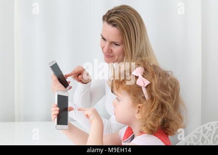 Une mère montrant son enfant la numérisation avec smartphone Banque D'Images