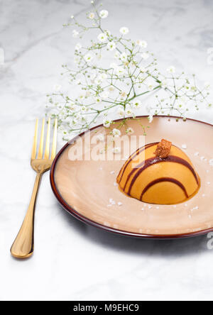 Restaurant de luxe caramel dessert sur assiette avec la fourchette d'or et de fleurs Banque D'Images