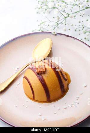 Restaurant de luxe caramel dessert sur assiette avec la fourchette d'or et de fleurs Banque D'Images