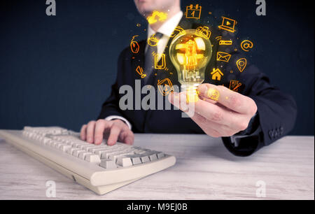 Un bureau commercial promouvoir ses idées de concept avec l'illustration des médias en ligne et les logos de l'appareil autour de l'ampoule en verre électrique. Banque D'Images