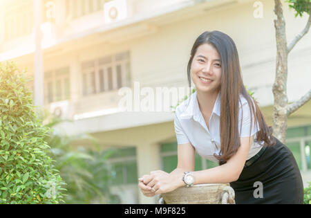 Jeune femme asiatique en uniforme et sourire étudiant looking at camera, heureux et vous détendre concept Banque D'Images