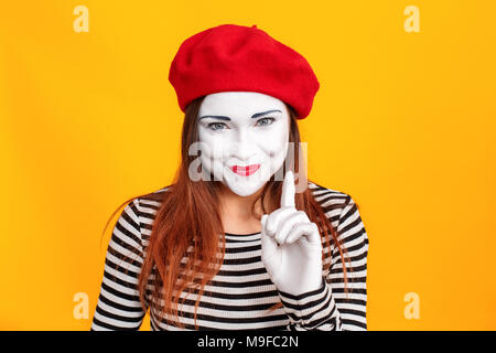 Closeup portrait of woman in mime rusé blouson rayé, doigt vers le haut et avoir idée. Émotions et sentiments concept. Tourné à l'intérieur, fond jaune Banque D'Images