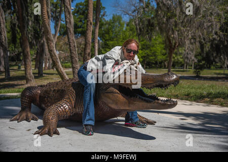 Jolie tête rouge portant des lunettes de soleil fille posant avec un alligator Bronze Statue Banque D'Images