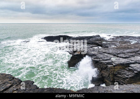 Les vagues puissantes se briser sur les rochers du littoral, la ligne avec un océan vert et moody sky Banque D'Images