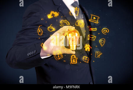 Un bureau commercial promouvoir ses idées de concept avec l'illustration des médias en ligne et les logos de l'appareil autour de l'ampoule en verre électrique. Banque D'Images