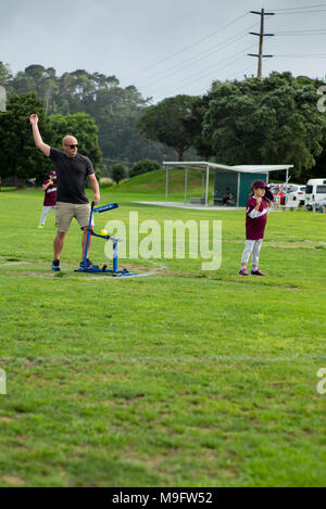 Un adulte utilise un pitching machine pitching suivantes bien qu'avec une action de bras au junior de softball. Banque D'Images