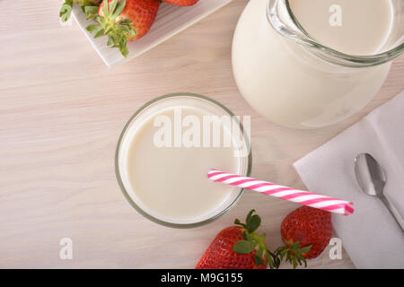 Le lait et les fraises de petit-déjeuner sur une table de cuisine en bois blanc. Composition horizontale. Vue d'en haut Banque D'Images