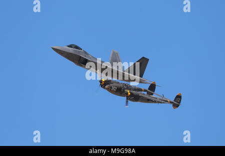 Lancaster, États-Unis. Mar 25, 2018. Un United States Air Force F-22 Raptor fighter jet vole à côté d'une Deuxième Guerre mondiale P-38 Lightning avion à hélice. Les deux appareils ont été construits par Lockheed (maintenant connue sous le nom de Lockheed Martin). Credit : Kilmer Media/Alamy Live News Banque D'Images