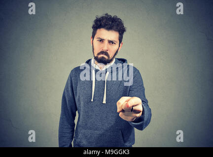 Jeune homme triste avec barbe pointant indiquant la culpabilité et le blâme de l'appareil photo en colère. Banque D'Images