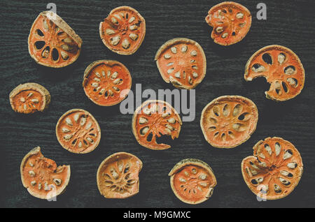 Les herbes séchées et séchées fruit de bael, vue de dessus de bael sec sur le plancher en bois, des tranches de fruit de bael pour faire du jus bael sur le sombre tableau. Banque D'Images