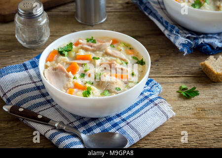 Soupe Poulet et riz sauvage. Frais fait maison soupe crémeuse au poulet, légumes et riz sauvage dans un bol blanc close up. Banque D'Images