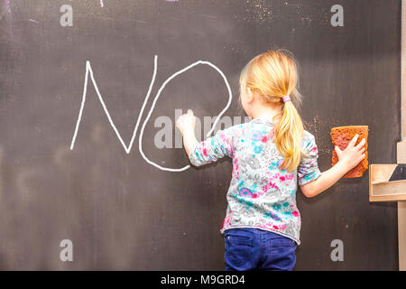 Cute little girl écrit sur tableau dans une salle de classe Banque D'Images