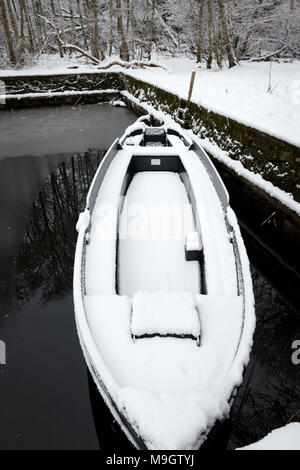 Bateau amarré seul couvert de neige dans le petit point d'entrée du lac Banque D'Images