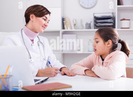 Médecin remplit carte du patient girl et lui demande à propos de Santé in medical office Banque D'Images