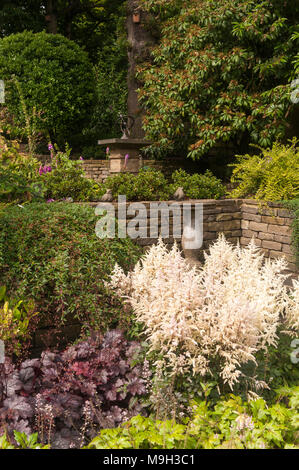 Petite terrasse avec cadran solaire en pierre, bain d'oiseaux, soulevé les frontières, d'arbustes et plantes - belle, traditionnelle, jardin paysagé - Yorkshire, Angleterre. Banque D'Images