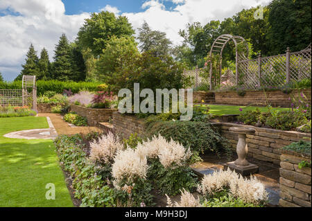 Cultures en terrasses, des plantes à fleurs sur la frontière, pelouse, murs en pierre, de treillis en bois arch & arbour - beautiful, conçu, aménagé, le jardin - Yorkshire, Angleterre. Banque D'Images