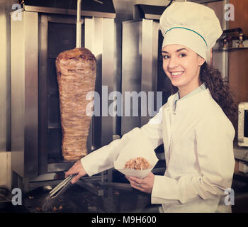 Cheerful young female chef préparer shawarma au bistro Banque D'Images