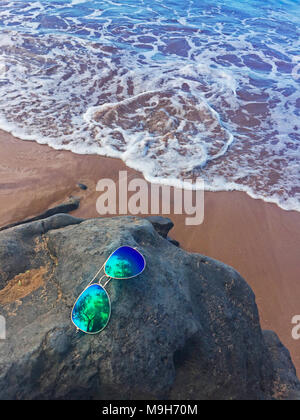 Du sable, un roc, lunettes de soleil, une douce vague, et clair, bleu de l'eau à la plage -- une image parfaite de tout ce qui est attrayant à Maui, Hawaii, USA Banque D'Images