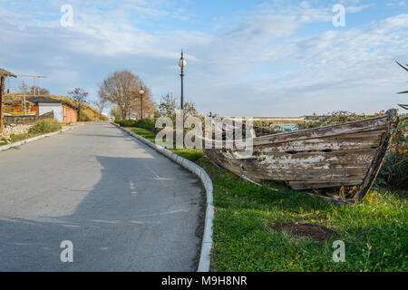 Épave bateau dans le côté de la route, avec de l'herbe à l'intérieur de , contre un ciel nuageux ciel bleu , Banque D'Images