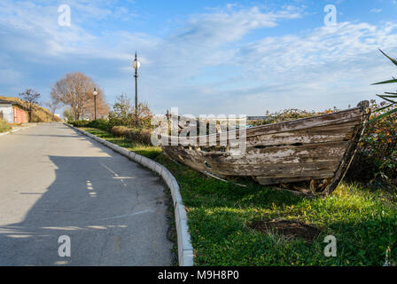 Épave bateau dans le côté de la route, avec de l'herbe à l'intérieur de , contre un ciel nuageux ciel bleu , Banque D'Images