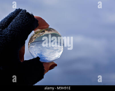 Woman's hand holding bille de verre avec vue panoramique sur la mer et le ciel/ Concept pour l'environnement Banque D'Images