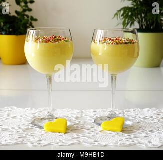 Avec deux verres de couleur crème vanille décoré de Nutrifer et jaune en forme de coeur cookie sur la table de cuisine Banque D'Images