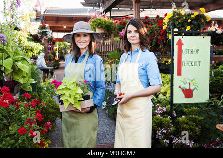 Caucasian woman propriétaire de centre de jardin pépinière avec un jeune employé. Banque D'Images