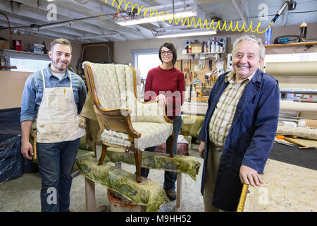 Young man rembourreur et sa doublure de l'équipe de jeunes qui travaillent sur une chaise ancienne. Banque D'Images