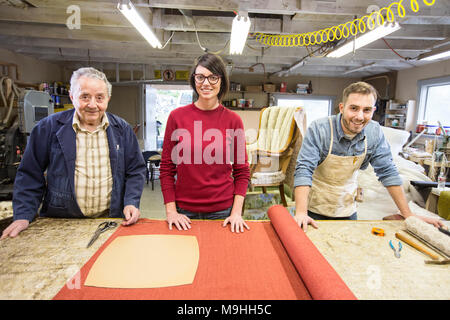 Young man rembourreur et sa doublure de l'équipe de jeunes qui travaillent sur une chaise ancienne. Banque D'Images