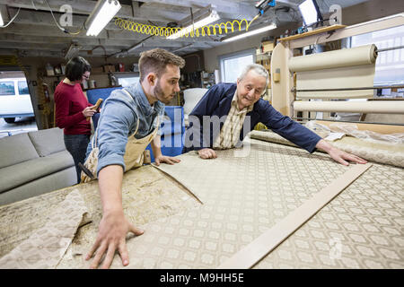 Young Caucasian man apprendre l'art d'upholsery d'un senior male tapissier. Banque D'Images