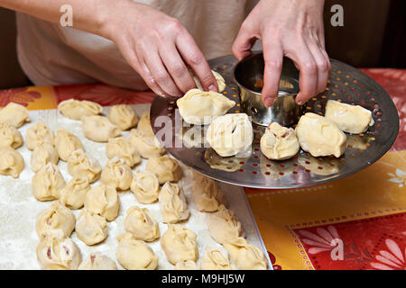 Mains de femmes avec des boulettes manti et plate-forme pour la cuisson Banque D'Images