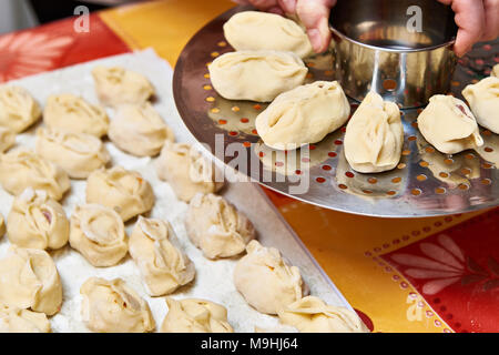 Mains de femmes avec des boulettes manti et plate-forme pour la cuisson Banque D'Images