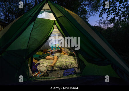 Une mère lit une histoire à ses enfants dans une tente. Banque D'Images